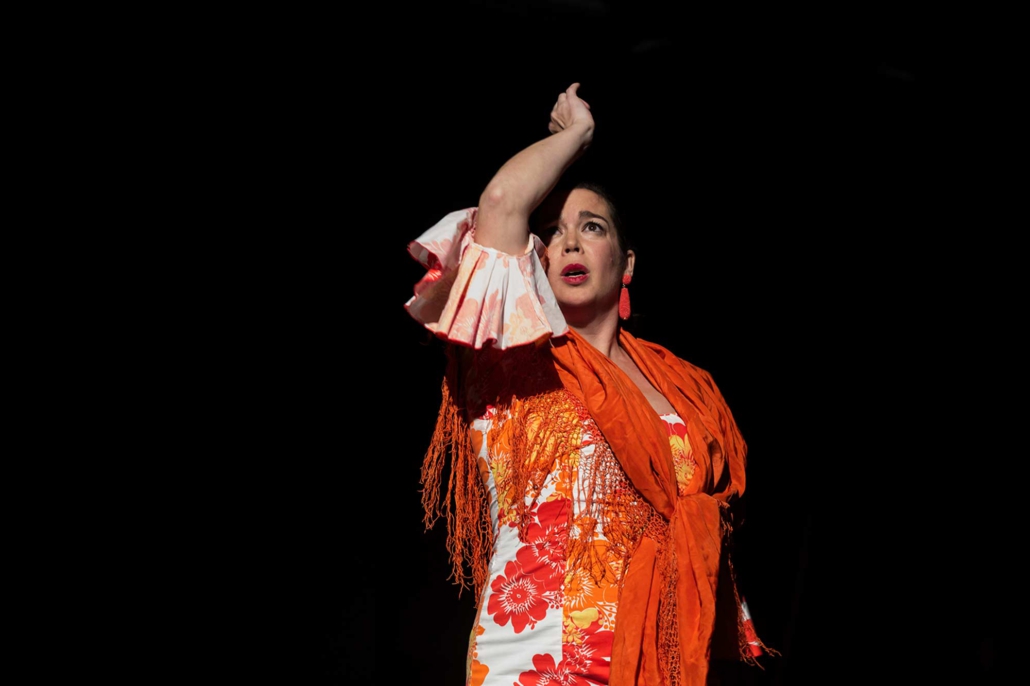 Pilar Murube – Corazón Partío Pilar Murube während der Tanzperformance Corazón Partío in einem floralen Kostüm mit orangefarbenem Schal.