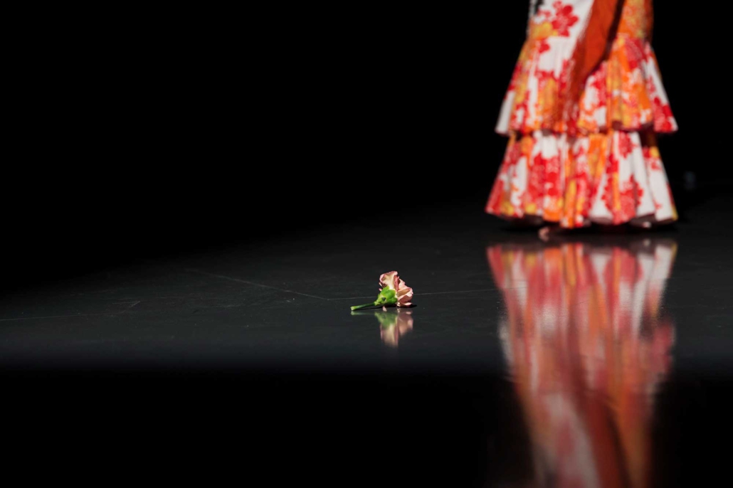 Pilar Murube – Corazón Partío Rose auf dem Bühnenboden während der Tanzperformance Corazón Partío, im Hintergrund das Kleid der Tänzerin.