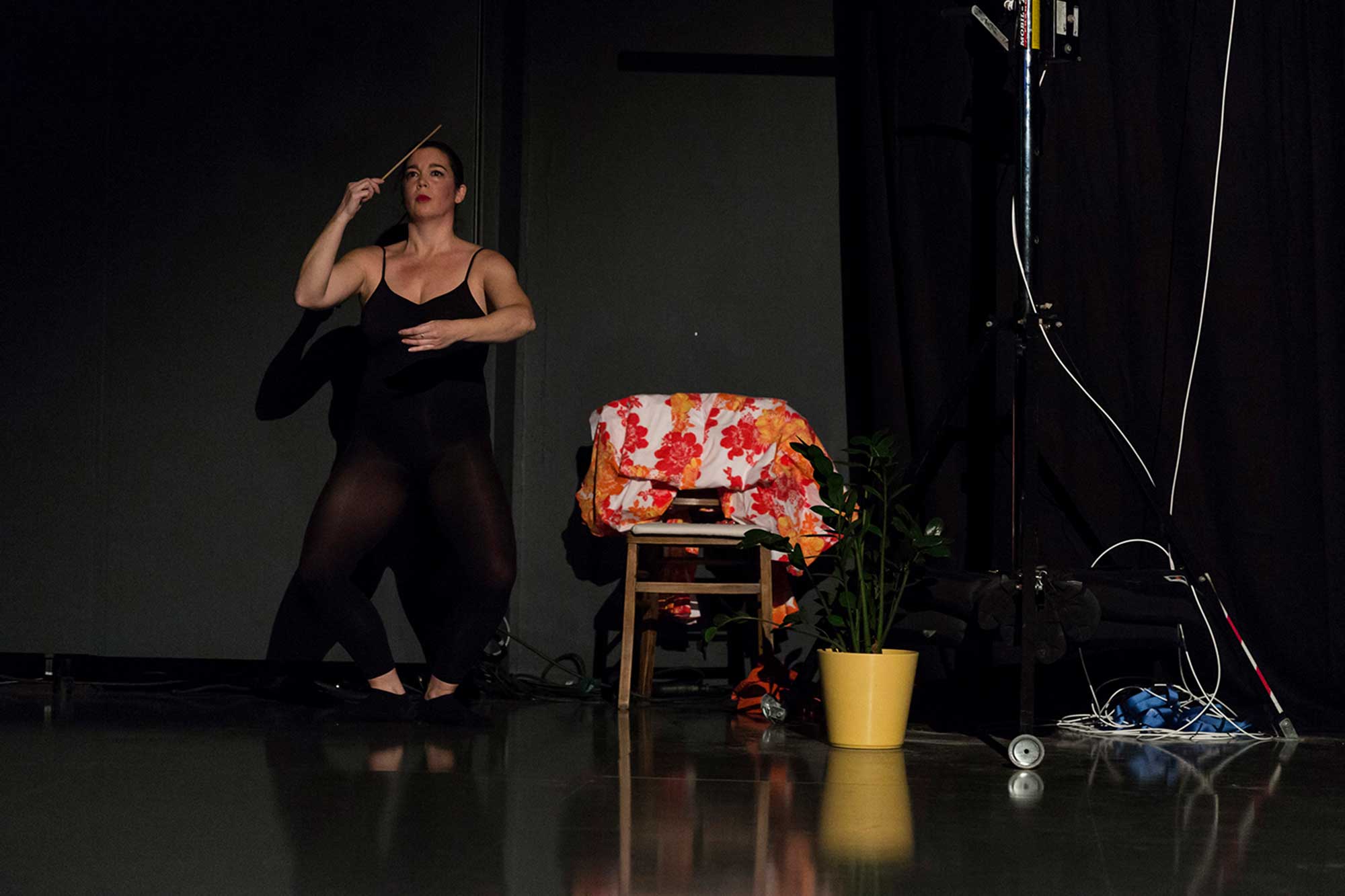 Pilar Murube während der Tanzperformance Corazón Partío auf der Bühne neben einem Stuhl und einer Pflanze.